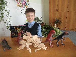 Олег с игрушками, изображающими различные виды динозавров